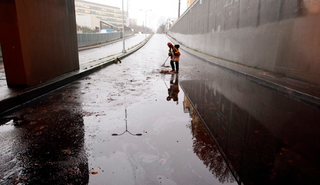 A Seattle Public Utility worker clears out a drain under Highway 99 where the low spot was closed to traffic after it flooded in November 2012. (Elaine Thompson/AP)